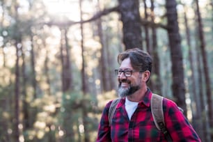 Close up portrait of confident bearded man in  outdoor park. Profile young handsome smiling bearded man Young adult hipster hiking forest - happy people enjoying nature and trees in weekend travel