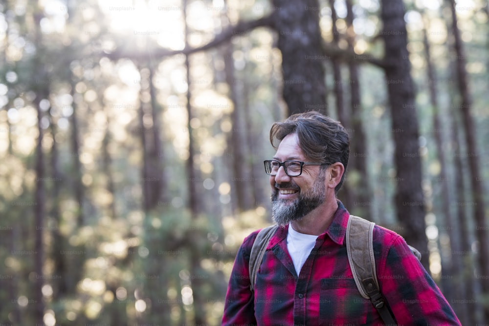 Close up portrait of confident bearded man in  outdoor park. Profile young handsome smiling bearded man Young adult hipster hiking forest - happy people enjoying nature and trees in weekend travel
