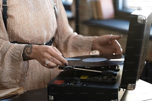 Primer plano de la mujer que pone el disco en el viejo tocadiscos, ella escuchando música en casa