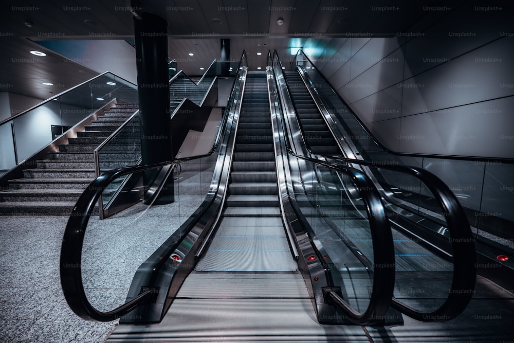 Uma foto frontal grande angular de duas escadas rolantes em um shopping center ou um terminal de aeroporto, ou um depósito de estação de transporte, com uma escada à esquerda; luz de néon, lâmpadas LED de teto brilhante