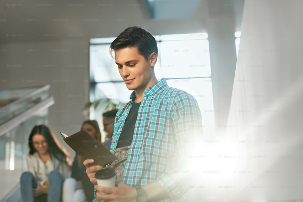 Young Man Learning, Reading Notes in Book. Student Studying And Drinking Coffee In College. High Resolution