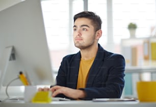 Young businessman looking at computer monitor and reading curious data