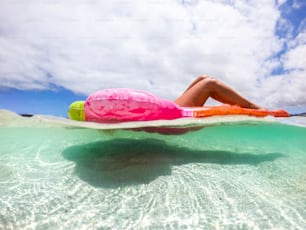 Underwater view of nice caucasian woman enjoying the summer holiday vacation relaxing on a coloured trendy lilo in the transparent caribe sea - people having sunbath at tropical beach