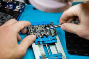 Pinzas en manos de un reparador profesional durante el trabajo con pequeños detalles de un teléfono inteligente roto