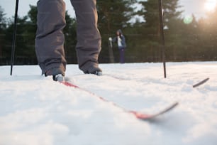 Legs of human standing on skis and moving forwards down ski track in snow