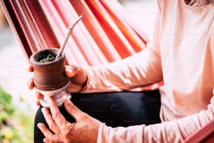 古い先輩の手の女性白人が木製のカップから自然なお茶を飲んでいるカラー画像の接写 - 代替の人々のための自然で健康的なライフスタイル