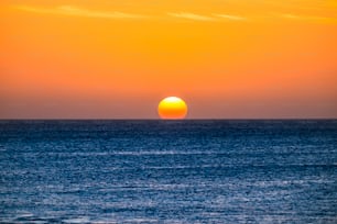 Perfect sunset moment when the sun touch the water in the middle of the ocean in summer vacation tropical island - romantic and beautiful natural outdoor background for vacation concept