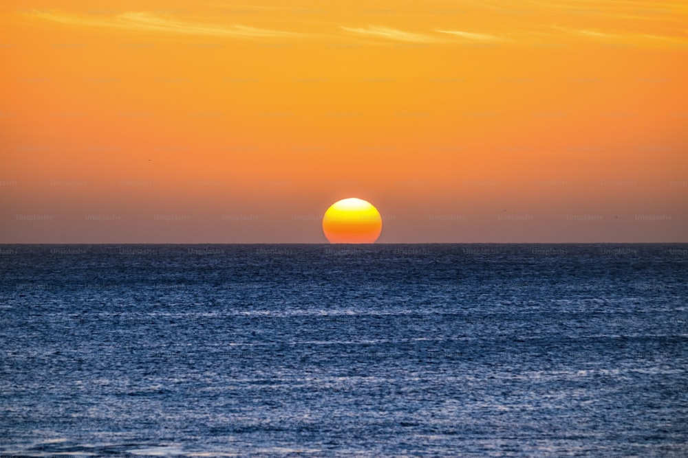 Perfect sunset moment when the sun touch the water in the middle of the ocean in summer vacation tropical island - romantic and beautiful natural outdoor background for vacation concept