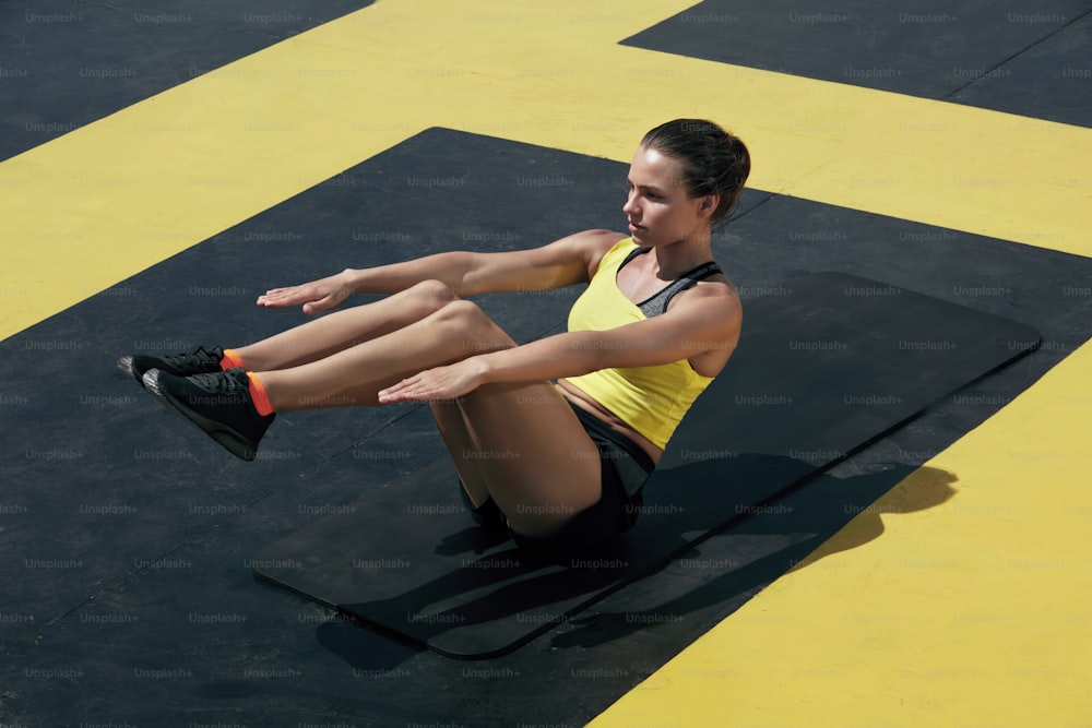 Mujer deportista haciendo ejercicio abdominal en gimnasio al aire libre. Modelo de chica de fitness haciendo ejercicio en la colchoneta de yoga, haciendo entrenamiento de los músculos del abdomen en el club de salud