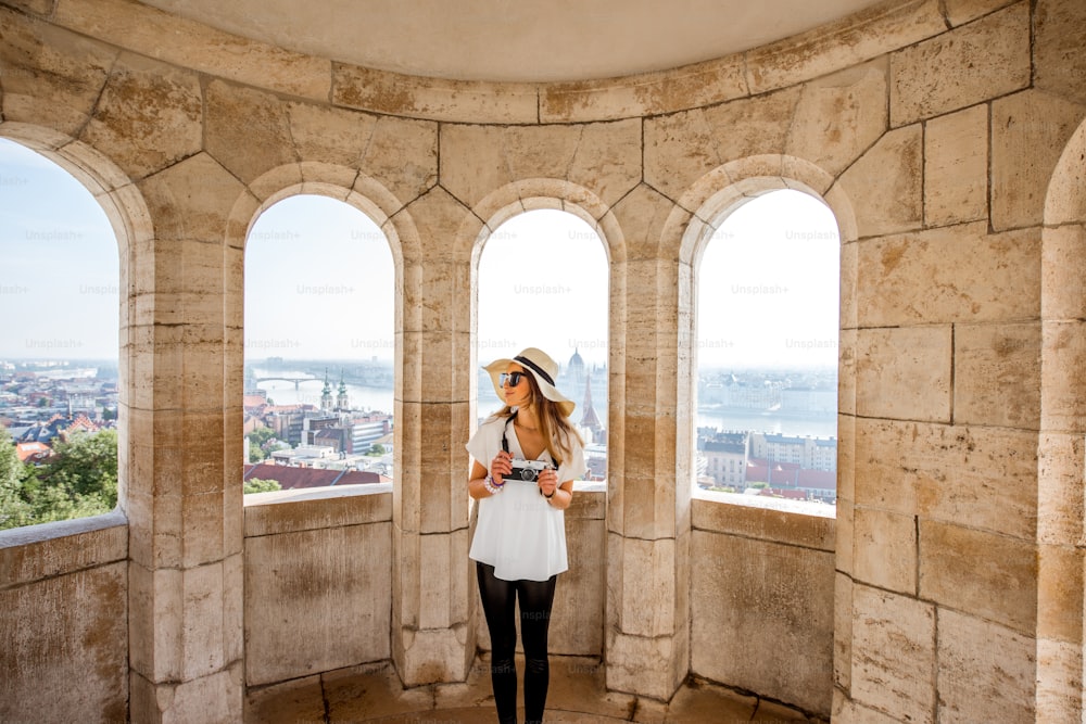 헝가리 부다페스트에서 여행하는 아치가 있는 테라스에서 도시 전망을 즐기는 젊은 여성 관광객