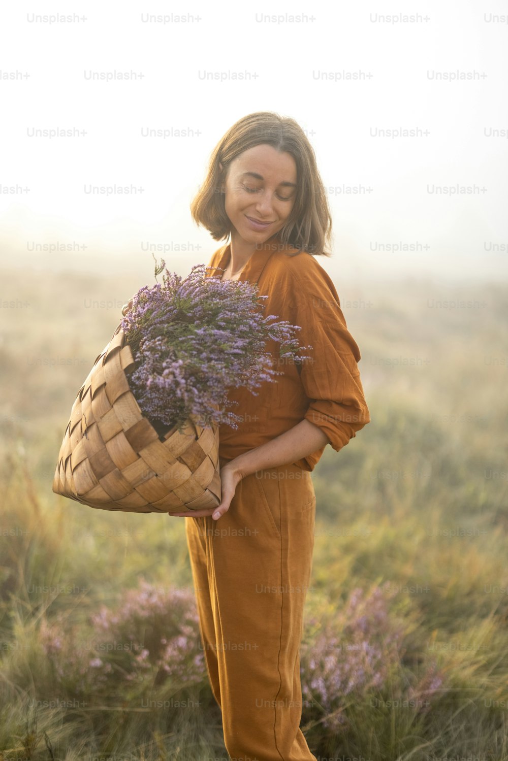 Portrait of a cute woman with a freshly picked up heather bouquet in the mountains in a foggy weather
