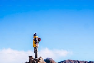 スポーツハイキングのライフスタイルでアウトドアレジャーを楽しむ人々 - 青い空を見ながら山の頂上に立つ男 - 明確な背景の成功と旅行のコンセプト