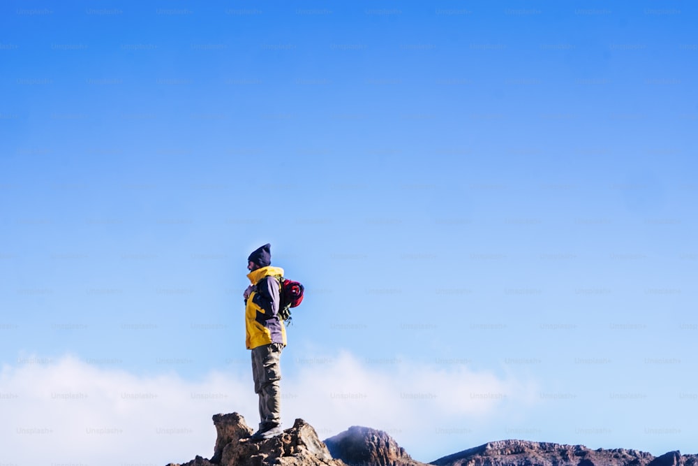 People enjoying the outdoor leisure ativity with sport hiking lifestyle - man standing on the top of the mountains looking at the blue sky - clear background success and travel concept