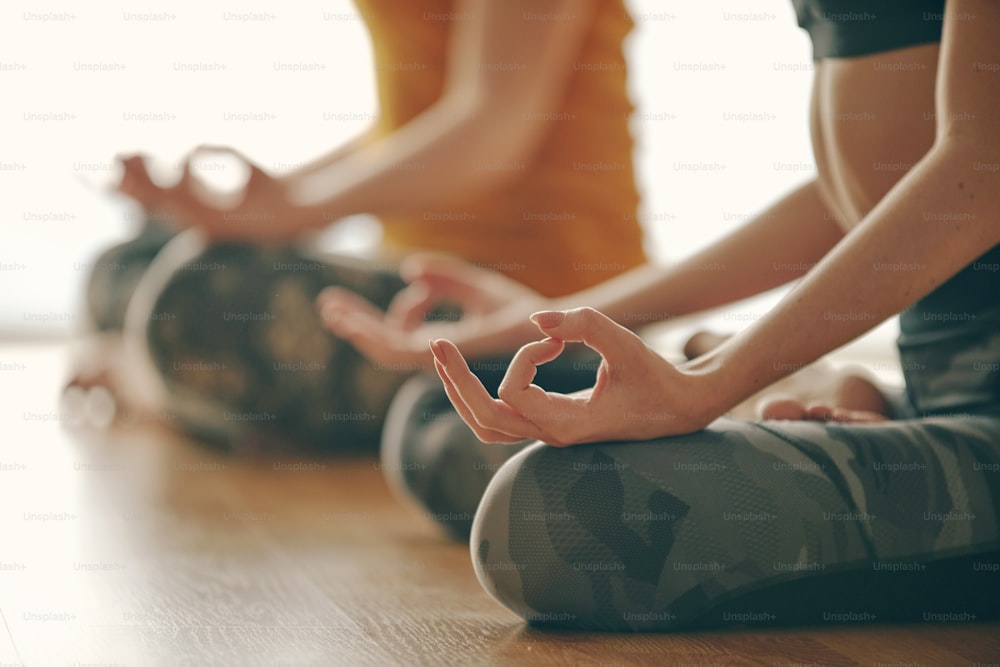 Close up in selective focus of two women hands gesture mudra, while doing yoga vinyasa flow, Padmasana, nirvana state of mind