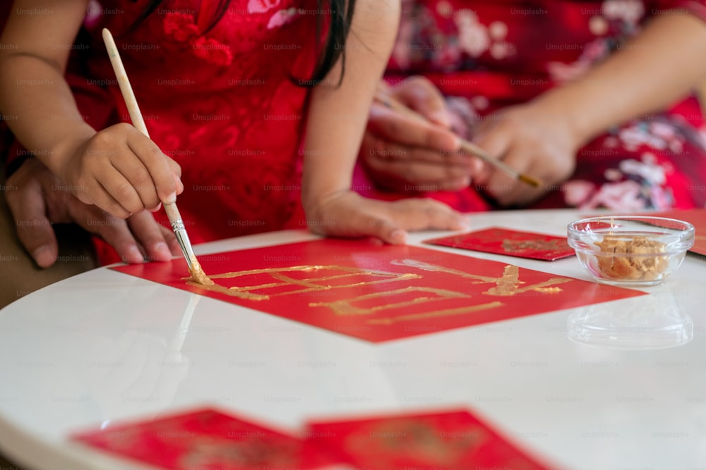 休日の前に新年のポストカードを作る赤いドレスの小さな女の子
