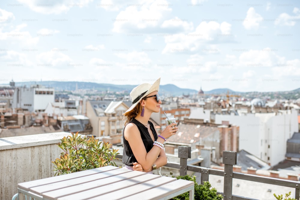 Mulher que aprecia a grande vista da paisagem urbana do terraço na cidade velha na cidade de Budapeste, Hungria