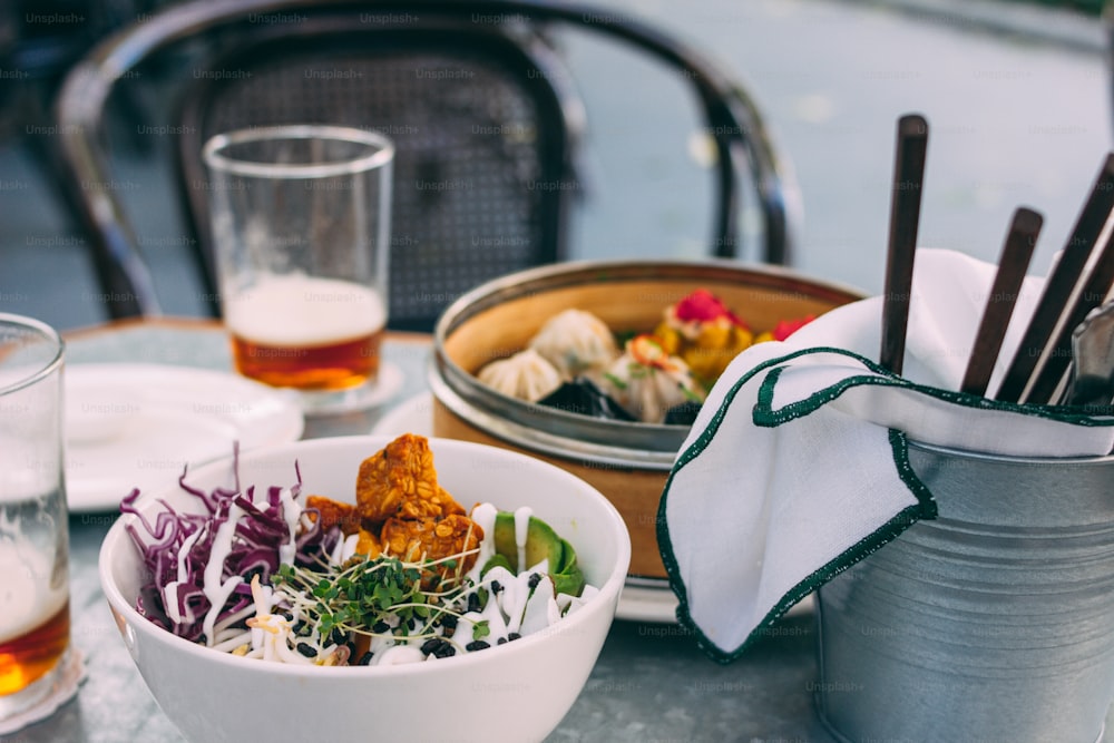Panasiatisches Essen - Gemüsesalatschüssel und verschiedene Dim Sums. Mittagessen für zwei mit Bier