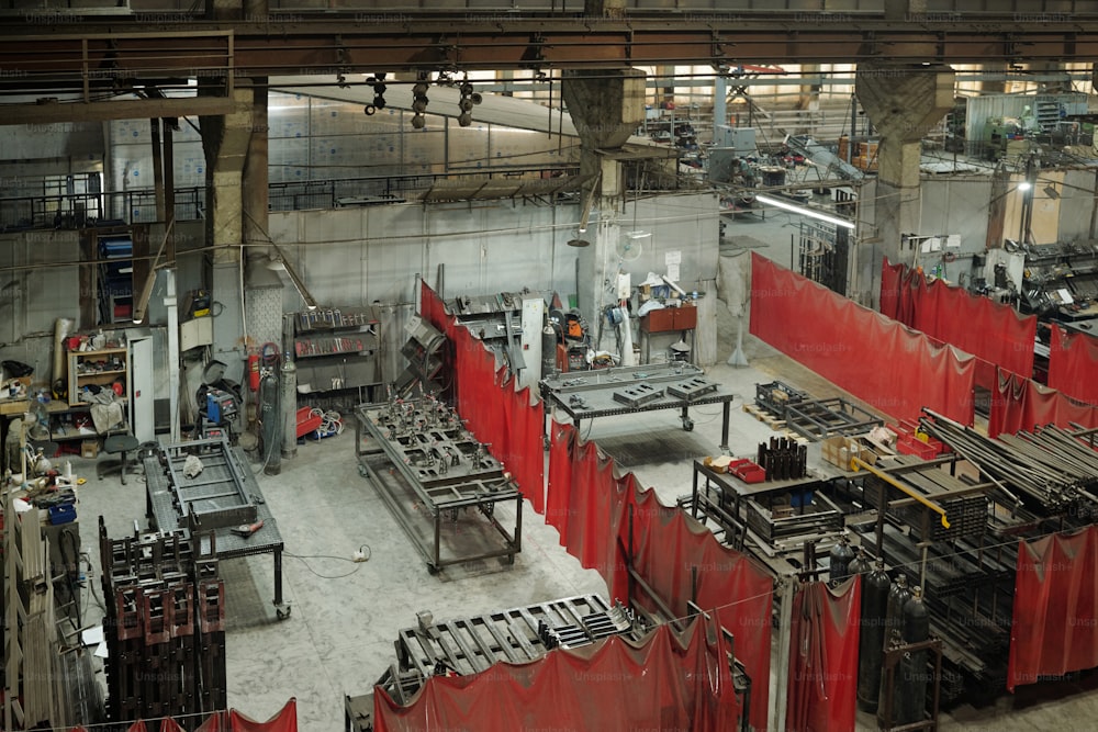 산업 공장 또는 제조소의 넓은 작업장 일부의 각도 위에는 빨간색 커튼으로 구분된 여러 섹션이 있습니다.