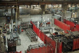 Above angle of part of spacious workshop of industrial plant or manufactory with several sections divided by red curtains