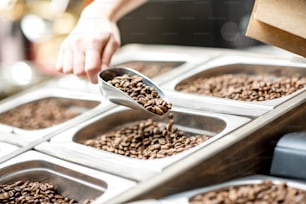 Filling paper bag with coffee beans from the metal trays for selling in the store
