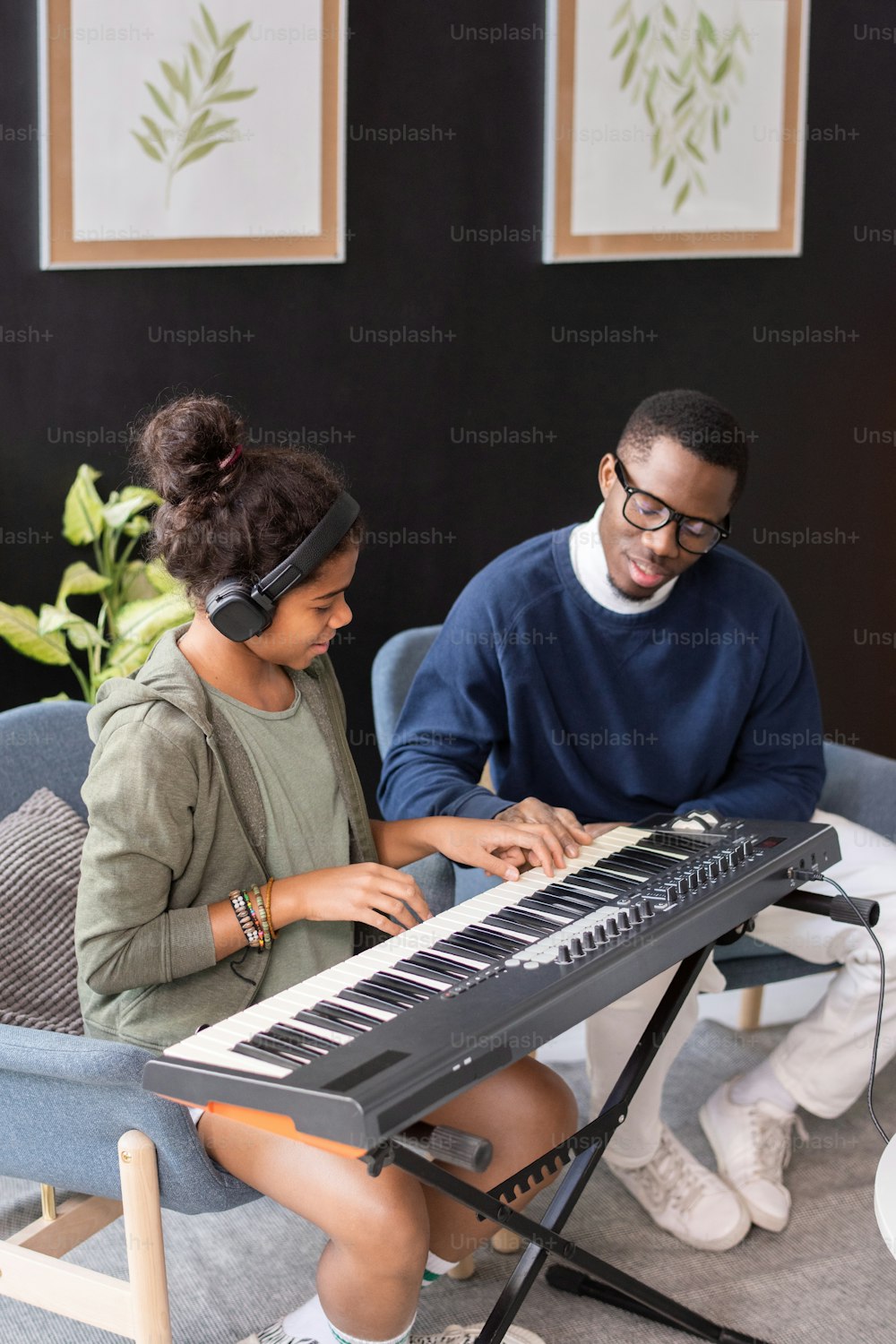 Estudante birracial contemporânea e sua professora de música de etnia africana tocando teclado musical