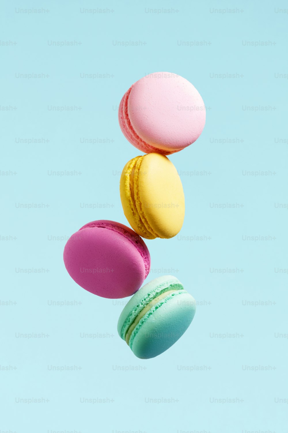 Biscuit macaron. Macarons colorés volants. Dessert français en mouvement tombant sur fond bleu. Haute résolution