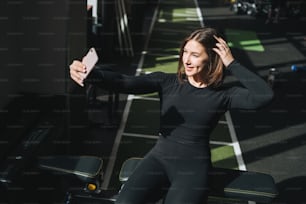 Portrait of resting Young brunette woman in sport active wear taking selfie in fitness club