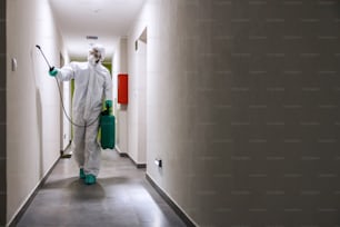 Arbeiter in sterilem Anzug und Maske Sterilisationshalle eines Gebäudes gegen Coronavirus/Covid-19.
