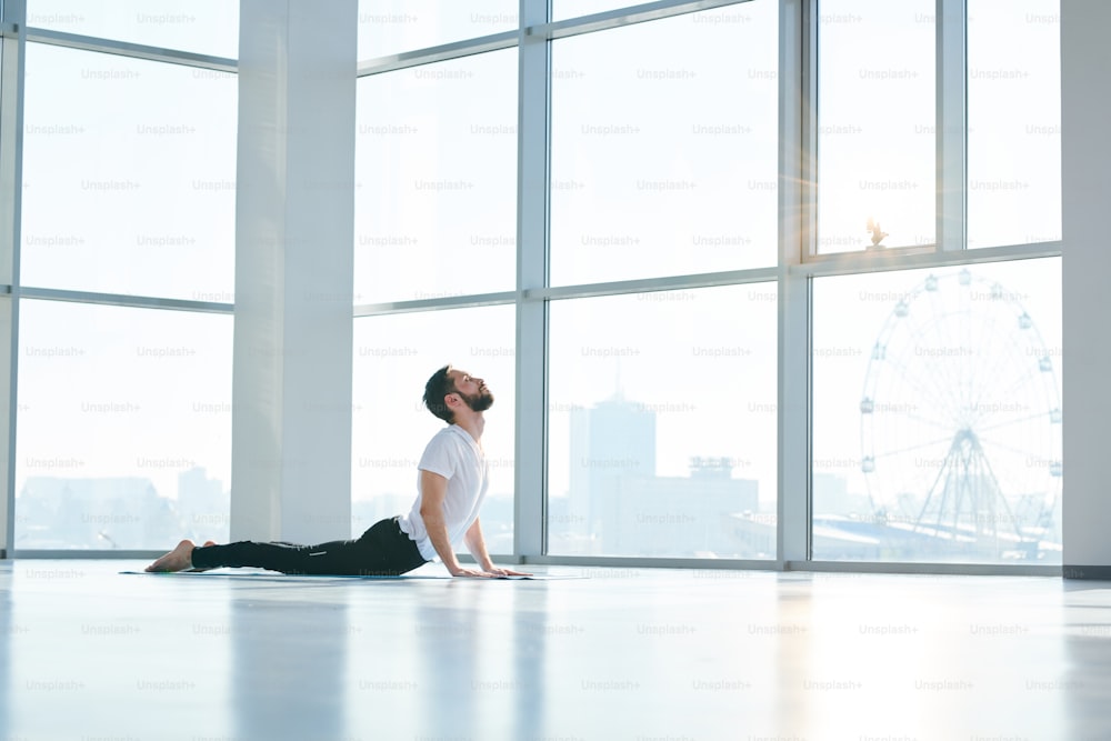 여가 시간에 요가 운동 중에 바닥에 누워 있는 동안 손에 균형을 잡는 운동복을 입은 젊은 활동적인 남자