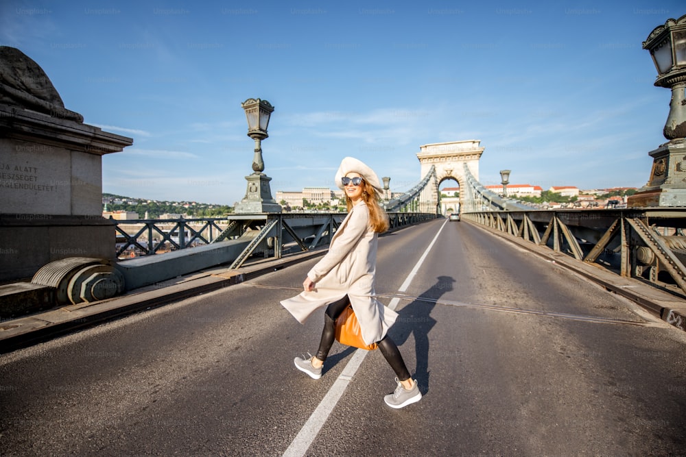 헝가리 부다페스트 시내를 여행하는 아침 햇살 동안 유명한 체인 다리를 걷는 젊은 여성 관광객