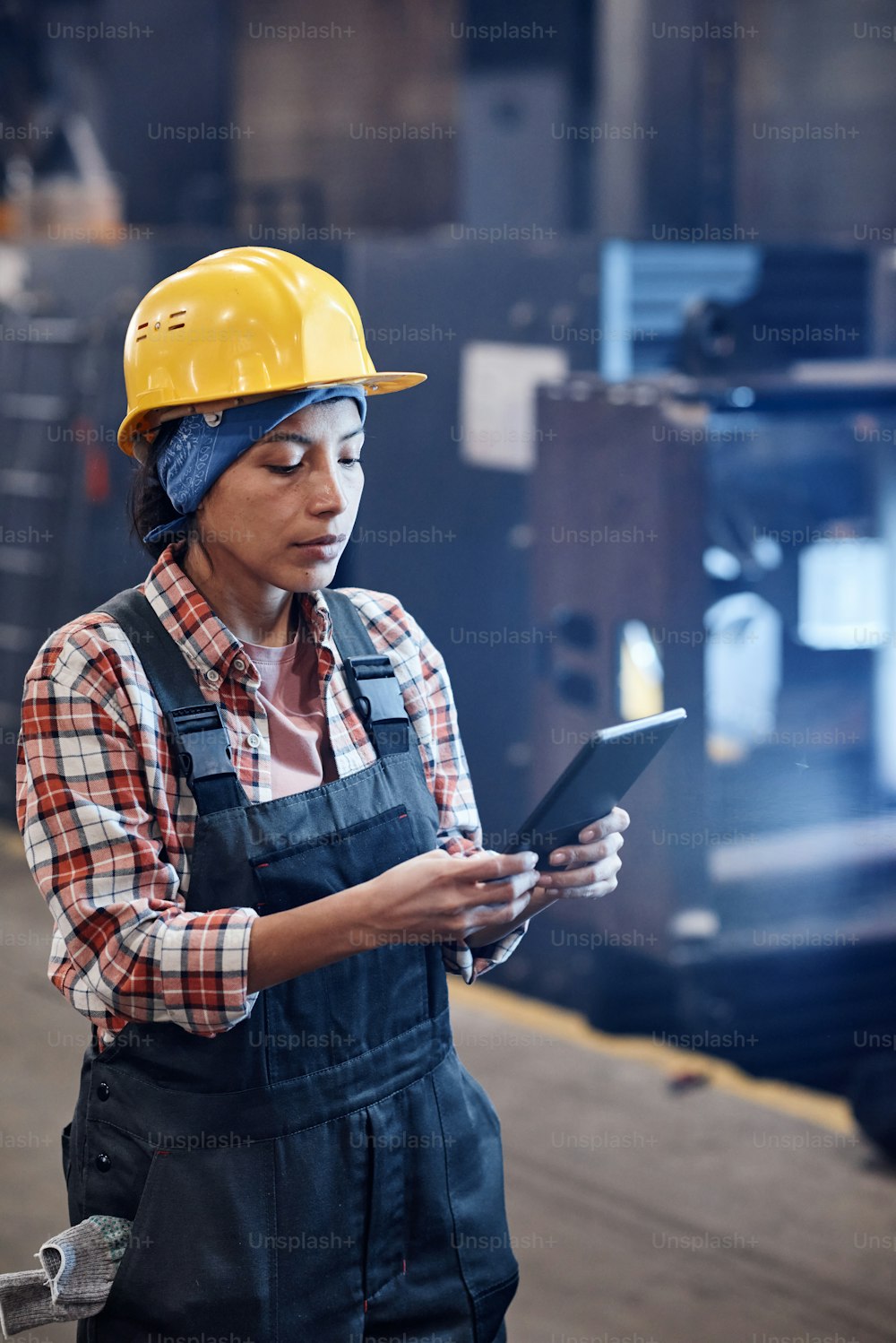 Serious female worker of industrial plant using tablet for check-up of online orders while standing in distribution warehouse