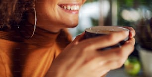 Closeup of mixed race woman holding cup of coffee and smiling.