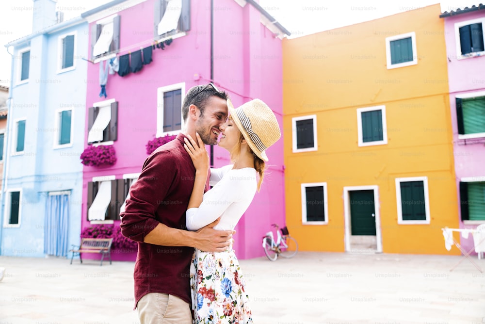 Couple of lovers kissing on city street in front of colorful buildings - Love and travel concept
