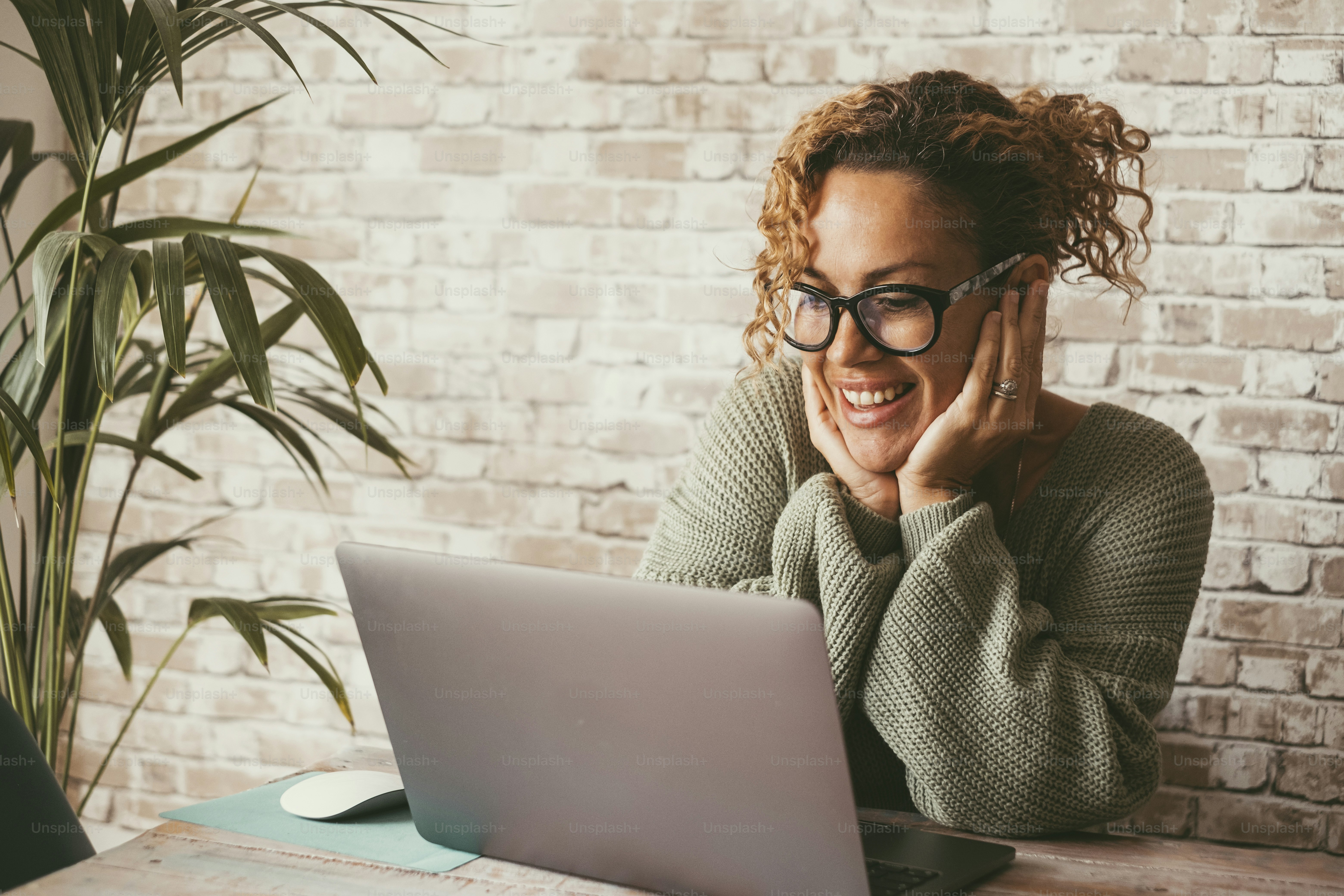 Cheerful attractive woman doing video call conference with computer connection. Home technology leisure and communication online. Female people smile at display at home. Modern lady use pc on the desk