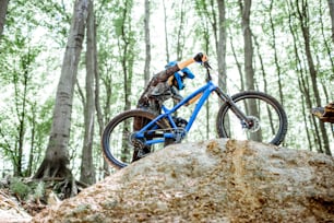 Professional cyclist carrying bicycle while riding off road in the forest. Concept of an extreme sport and enduro riding