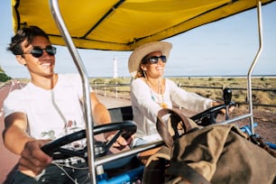 Adult mother and teenager son have fun together on a surrey bike during summer holiday vacation - family enjoy outdoor leisure activity together laughing and smiling