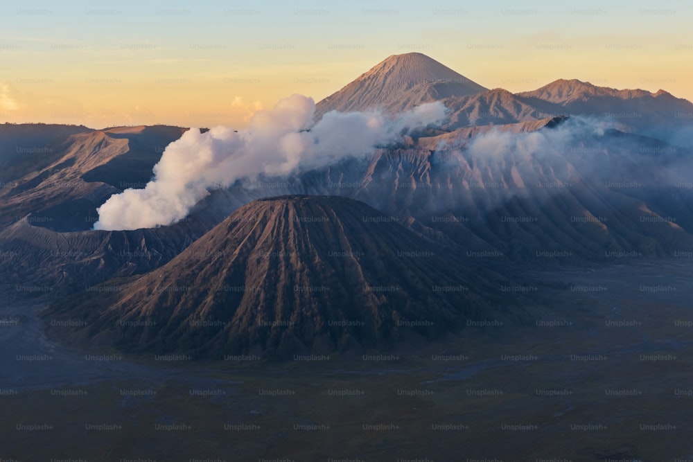 Nuages de fumée sur le volcan du mont Bromo, en Indonésie. Vue aérienne du mont comme un volcan actif avec un cratère en profondeur. Lever de soleil derrière les montagnes.
