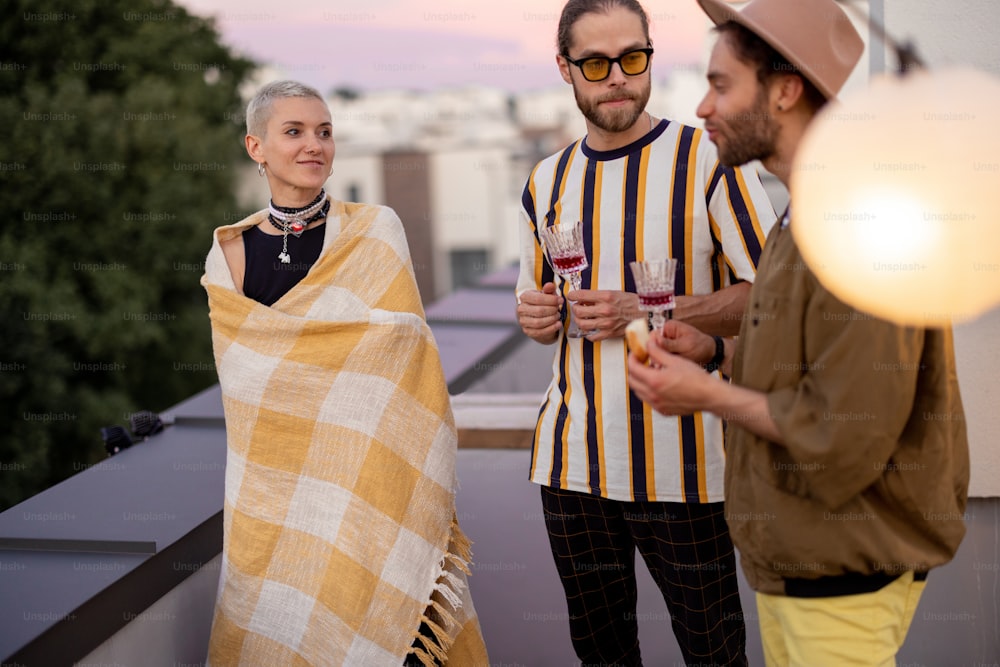 Young stylish friends hang out together talk and having fun on a rooftop party at dusk