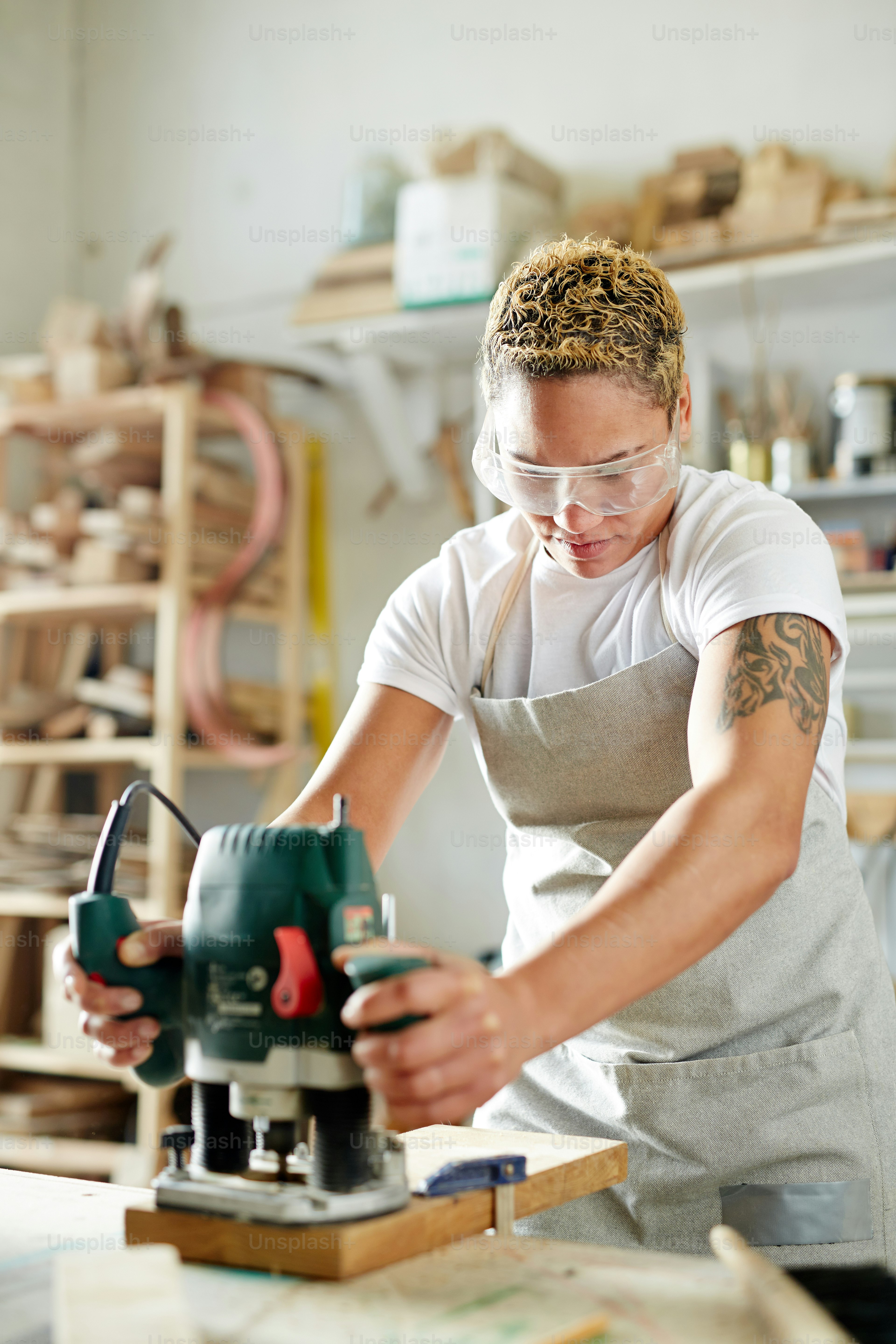 Woman in safety goggles and apron cutting board with cutter while ...
