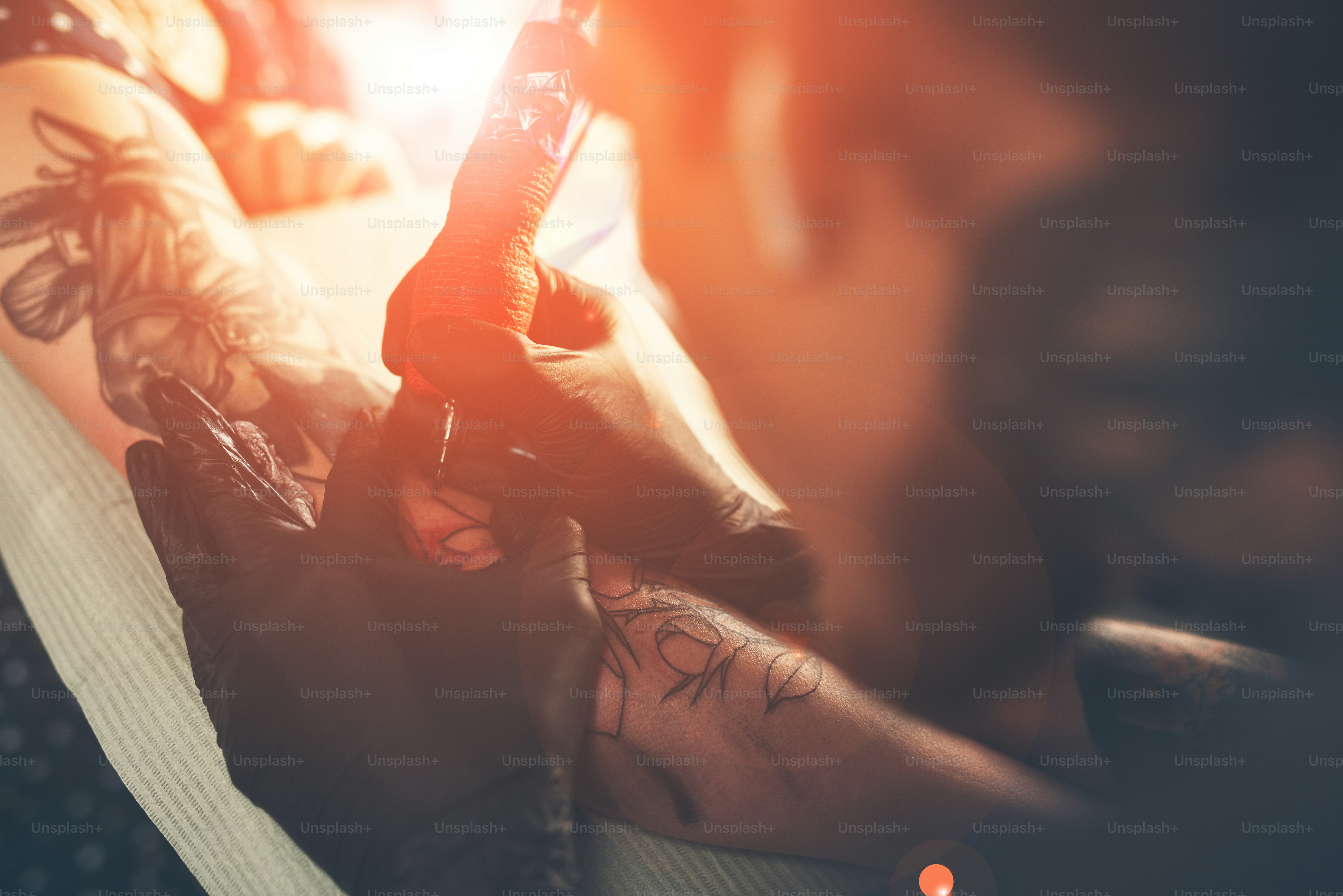 Un giovane ragazzo, batte un tatuaggio sulla mano della ragazza in un negozio di tatuaggi, macchina rotativa del tatuaggio, inchiostro nero, macchina del tatuaggio a fuoco"n