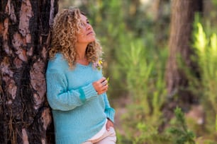 Retrato da bela mulher caucasiana adulta que desfruta da sensação com a natureza - pessoas e atividade de lazer da floresta de madeira - recreação alternativa feminina ativa com suéter azul da moda