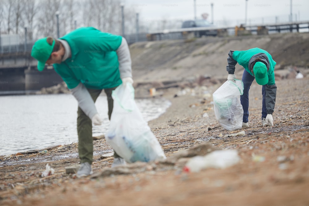 강변 해안에서 쓰레기를 줍어 환경을 보호하는 젊은이들