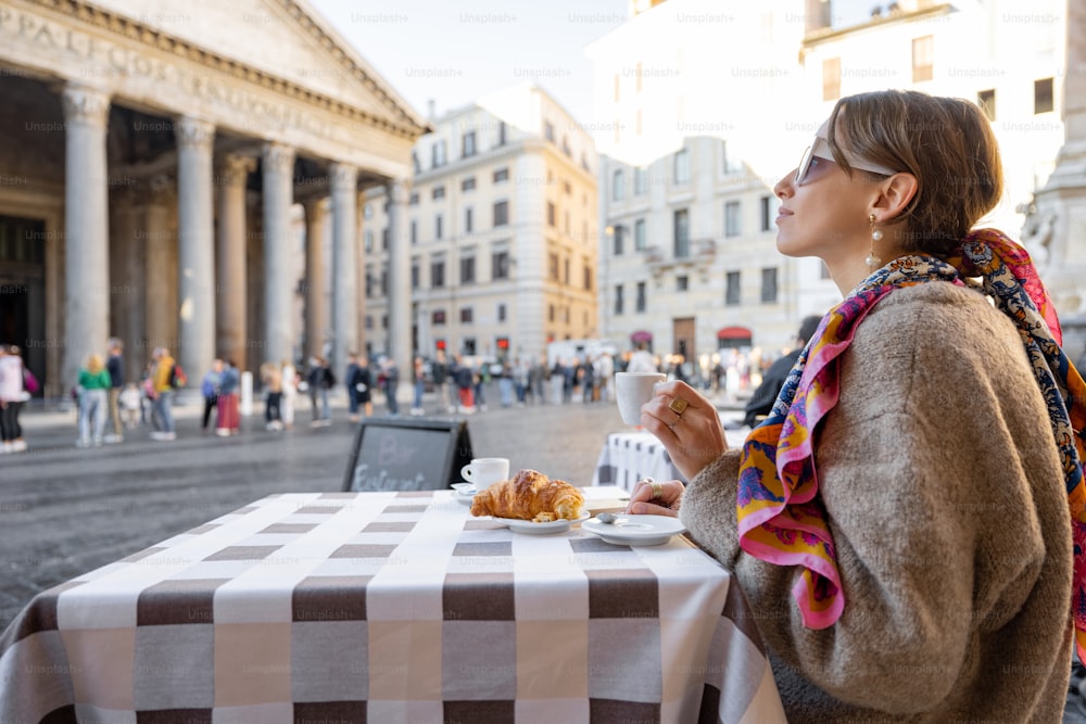 Frau frühstückt mit Croissant und Kaffee im Café im Freien in der Nähe des berühmten Pantheon-Tempels in Rom. Idee, Zeit in Rom zu verbringen. Konzept des italienischen Lebensstils und Reisens