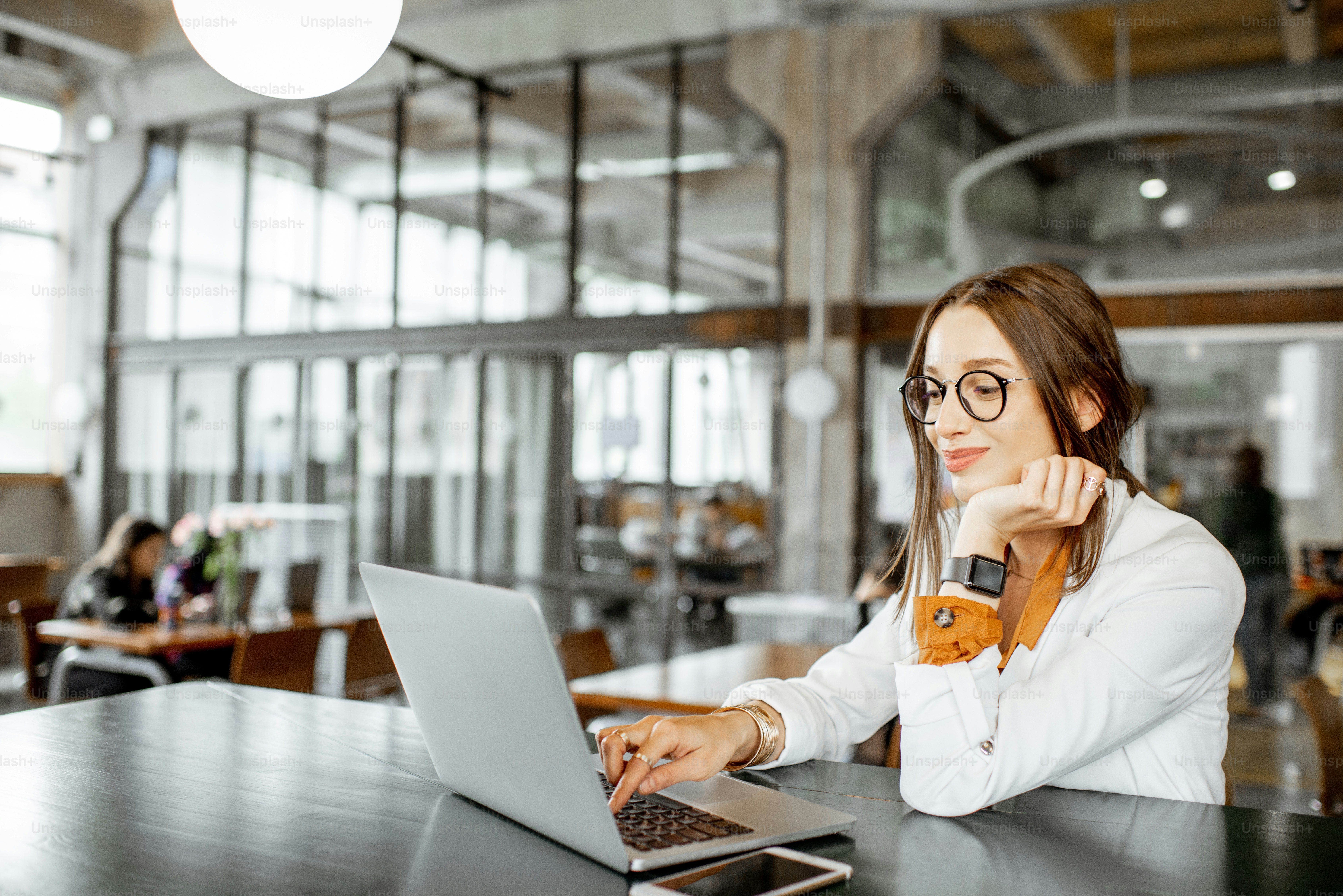 Retrato de uma mulher de negócios jovem e alegre sentada com laptop um bar ou escritório espaçoso moderno