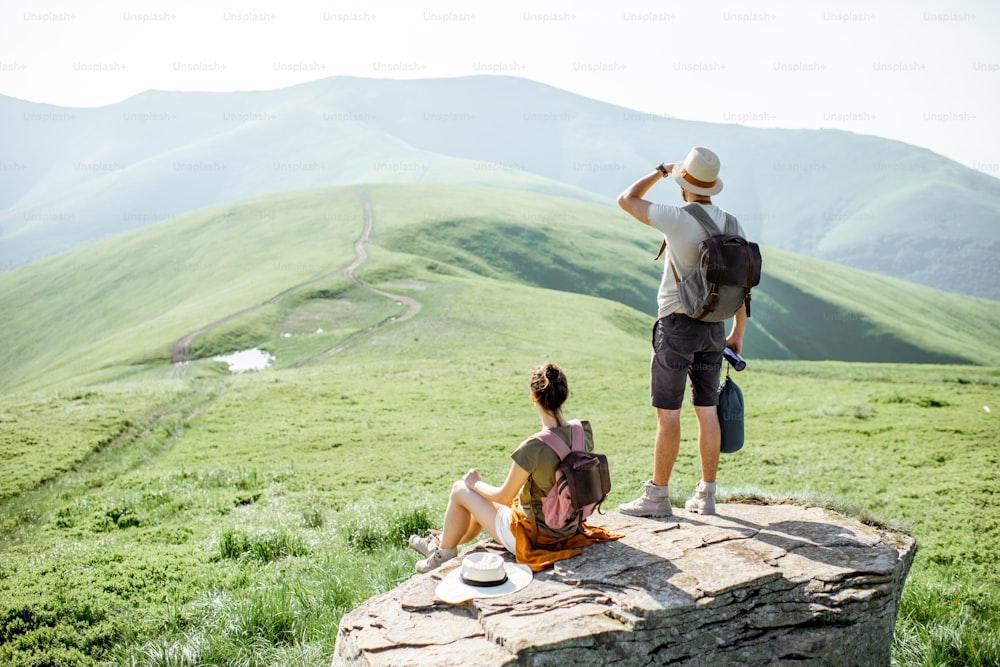 Coppia che gode di splendide viste paesaggistiche, riposando sulla roccia durante il viaggio in montagna durante il periodo estivo