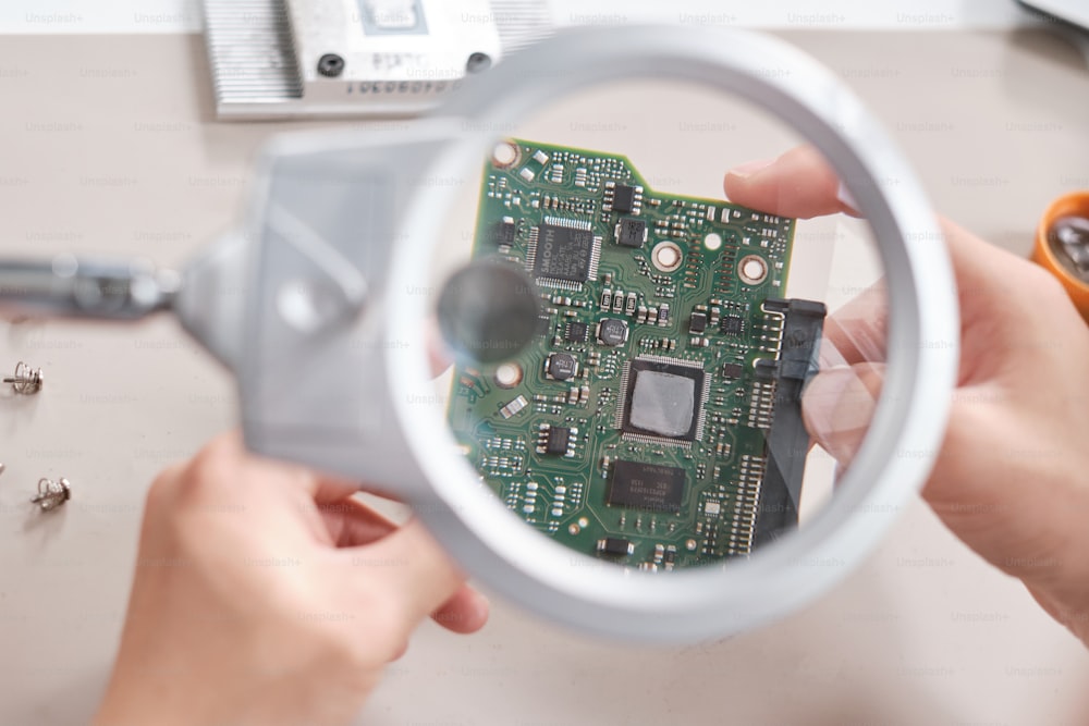 Magnifying glass and hands of technician holding circuit board of ...