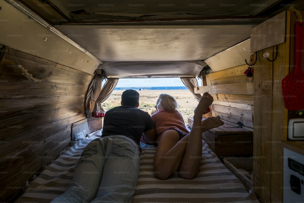 alternative waderlust vacation concept outdoor open air in camper van parking and sleeping in front of beaches and oceans in complete freedom couple caucasian enjoy her window just on the sand and are happy for this rare choice
