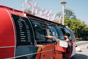 Coursier Yooung avec un énorme sac prenant la commande emballée donnée par le commis du food truck