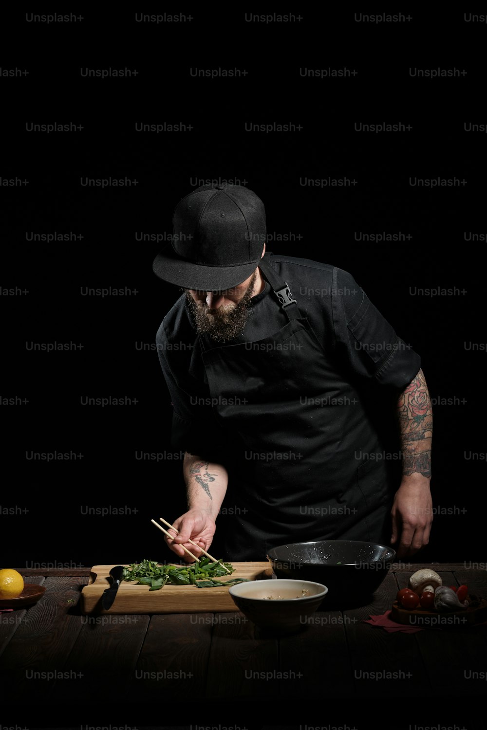 Ritratto di chef maschio che cucina pho bo in studio, su sfondo nero