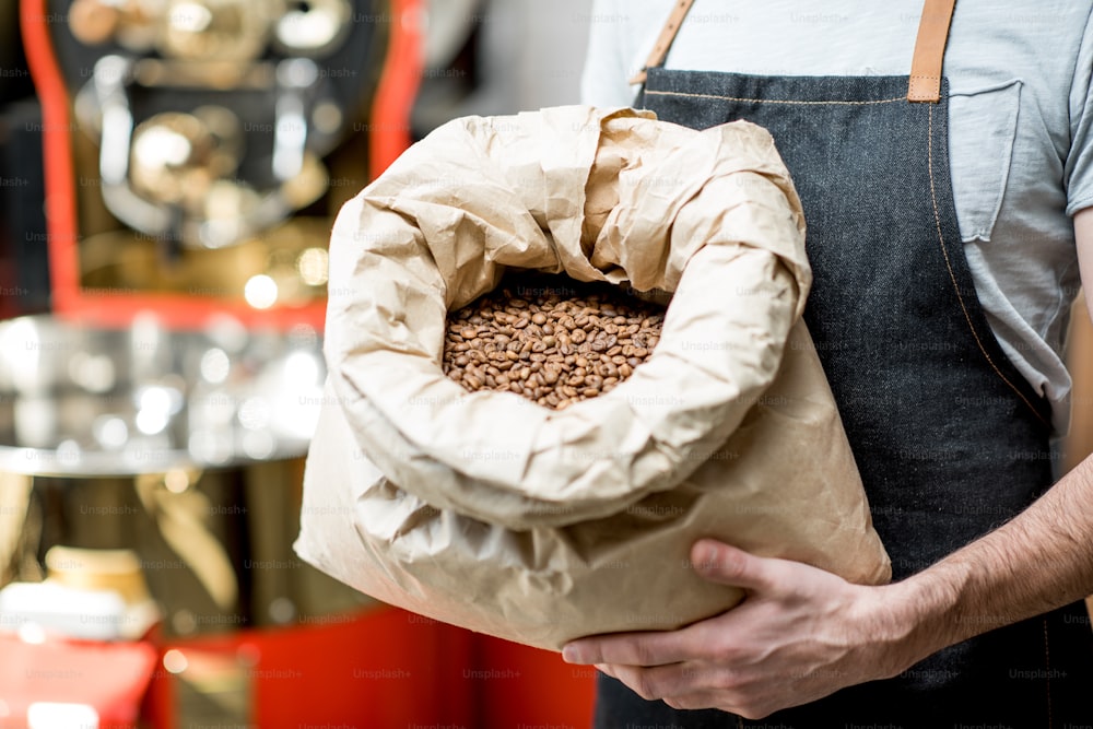 Barista segurando saco cheio com grãos de café torrados na cafeteria